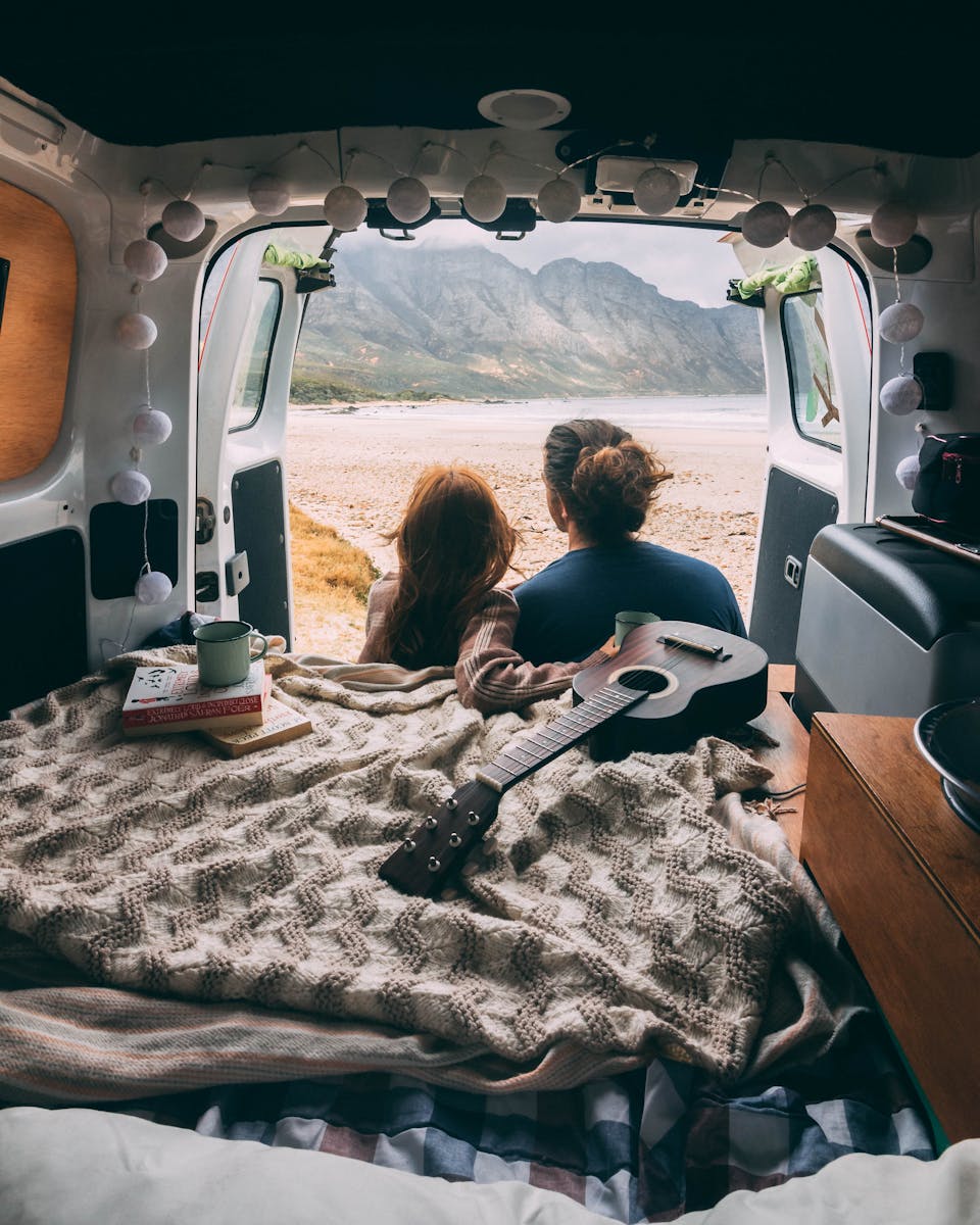 Backview of Couple sitting on a Camper Van