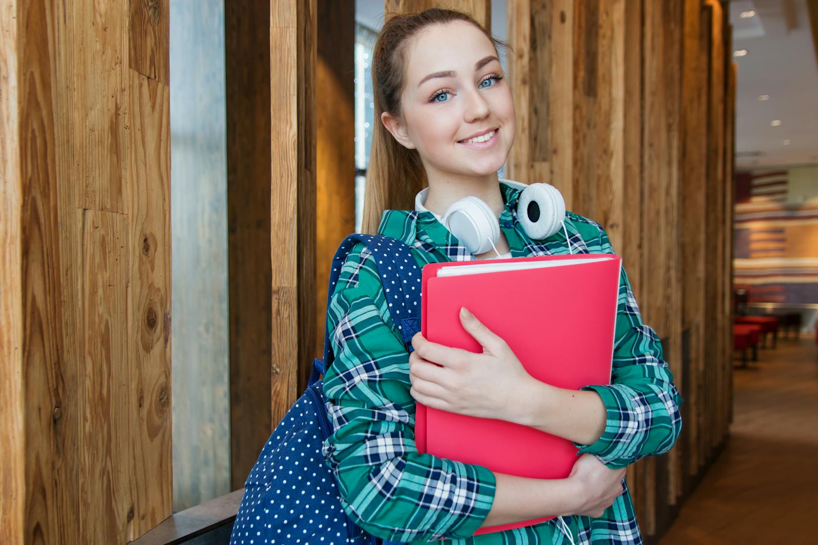 Smiling student holding book and wearing headphones, ready for study. renters